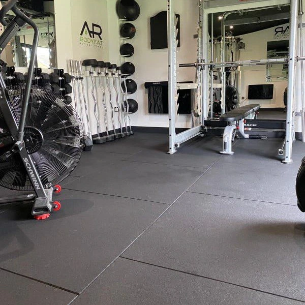 Gym flooring made of black rubber tiles is shown in a professional workout space