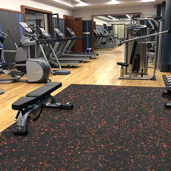 Gym flooring with orange and black speckled rubber matting is laid over a wooden floor in a gym